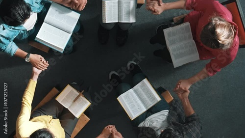 Top down view of diverse people holding hand and sitting in circle with bible book on lap. Aerial view of faithful prayer clasp hand and praying to god with faith, religion conceptional. Symposium.