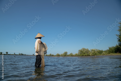 A fisherman carrying a fishing net on the seashore