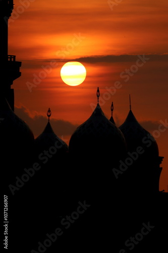 Silhouettes of domes and a mosque minaret with a sunset background