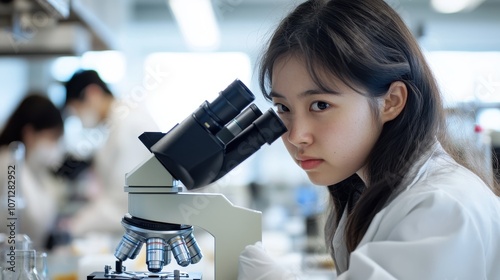 A Young Woman Looking Through a Microscope in a Lab photo