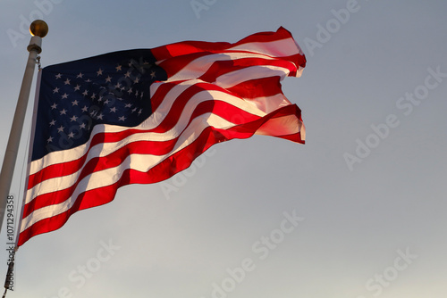 Waving Flag of America on blue cloudy sky background