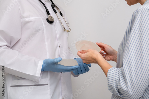 doctor and patient, exam, consultation in clinic office, holding breast enlargement implant in hands, plastic surgery, beauty enhancement, medical Mammoplasty and plastic surgery, mastopexy