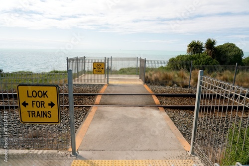 Pedestrian Railway Crossing by Ocean with ‘Look for Trains’ Sign