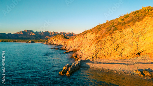 Warm sunset light illuminates San Luis Island off San Carlos Sonora, Mexico. Its surface full of sahuaros creates a beautiful contrasting landscape between desert and sea. photo