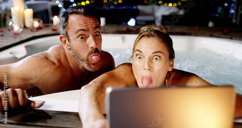 Couple, hot tub and selfie with tablet, funny face and night on holiday, love or post on web at luxury resort. Woman, man and tongue out for memory, app and comic profile picture for social network photo