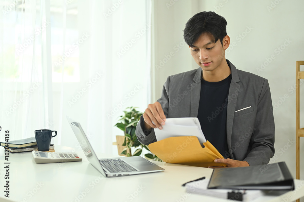 Concentrated businessman examining important documents at work desk Concentrated businessman examining important documents at work desk