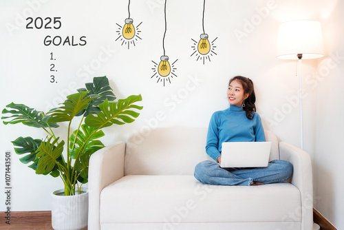 2025 goals with young woman pointing goals cheerful and happy new year with laptop on the sofa in living room.  Star together new year 2025 photo