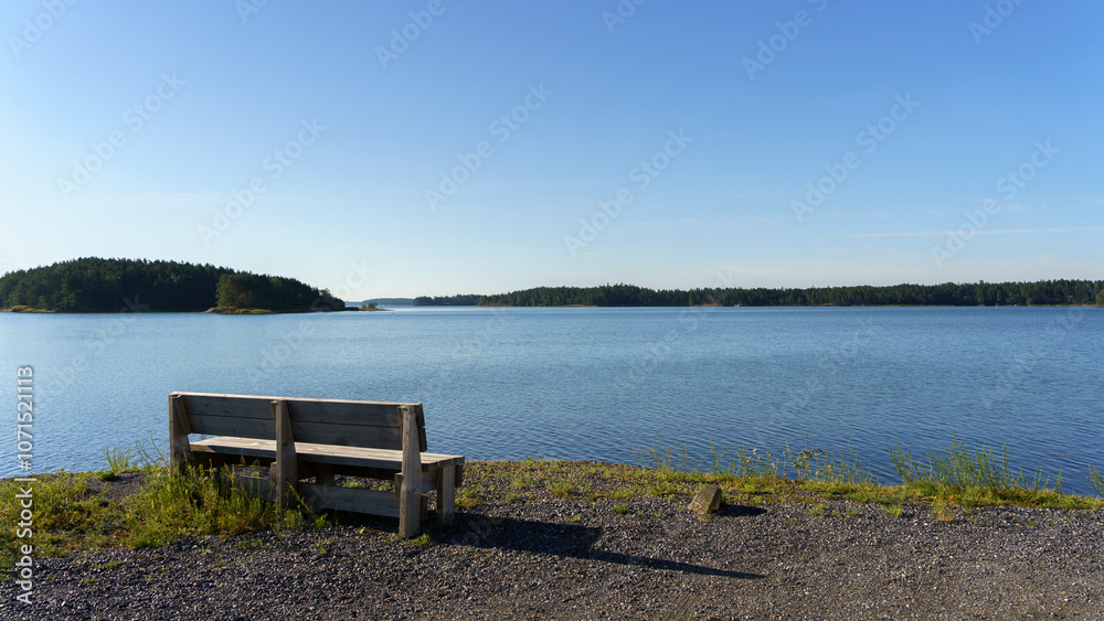 Tranquil wooden bench by a lake on a clear sunny day Tranquil wooden bench by a lake on a clear sunny day