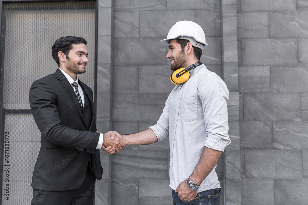 Project engineer and young businessman make high five for success business deal at outdoor office building project.
