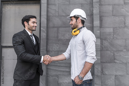 Project engineer and young businessman make high five for success business deal at outdoor office building project.