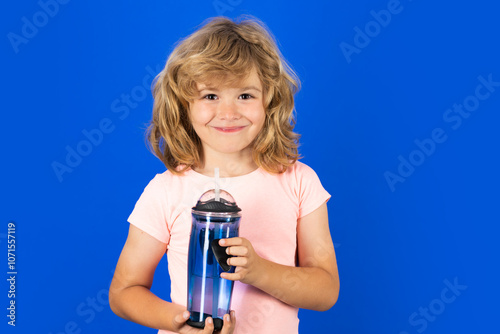 Kid drinking fresh water, isolated on studio background. Child holds glass of clear water. Healthy lifestyle, health care. Portrait of kid drinking water.
