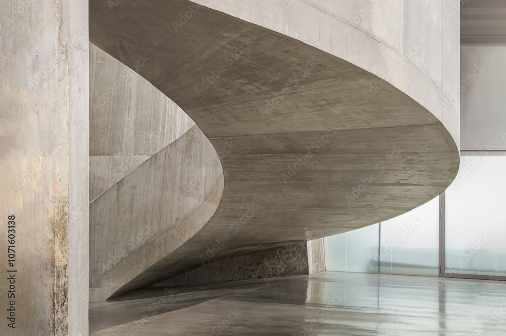 A curving flight concrete spiral staircase at Blavatnik Building of Tate Modern Switch House extension. Interior main curved stair at Tate modern its distinctive perforated, lattice brickwork.
