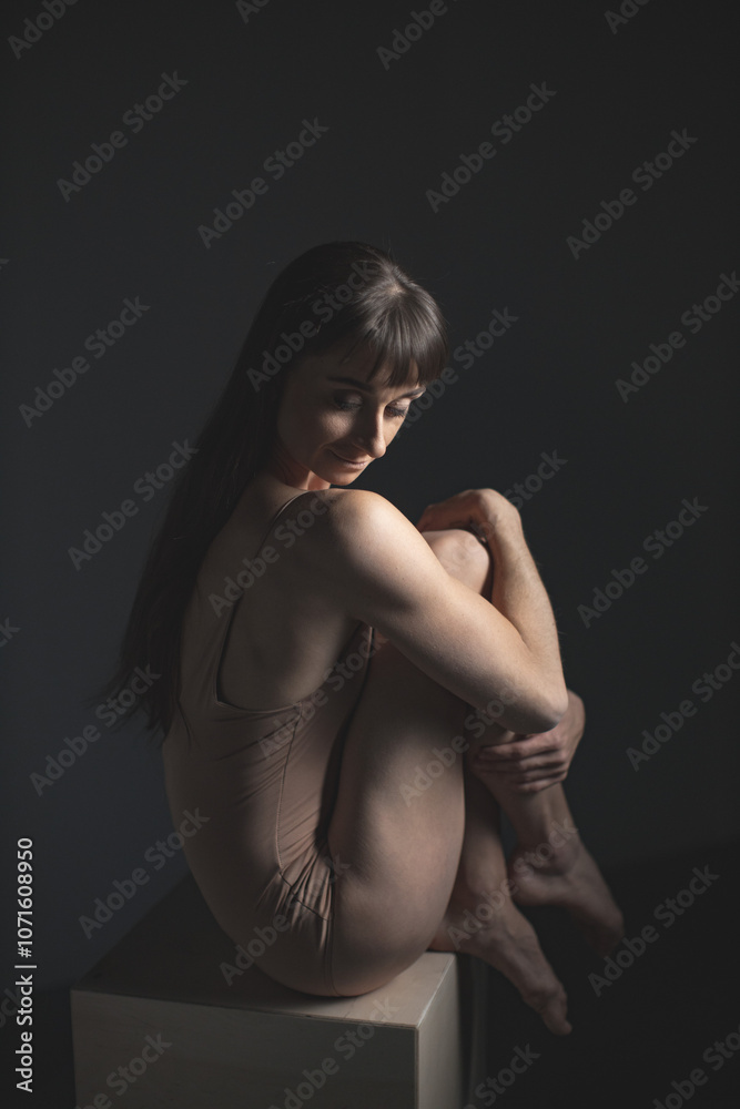 Naklejka premium Thoughtful Dancer Sitting Gracefully in Soft Studio Light