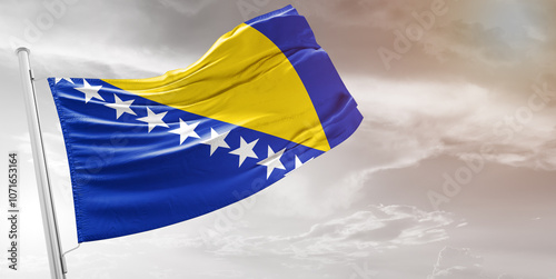 Bosnia and Herzegovina national flag cloth fabric waving on beautiful grey Background.