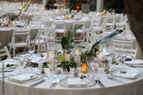 Beautifully arranged wedding reception table with candles, greenery, and elegant white tableware, ideal for sophisticated outdoor celebrations and event decoration.