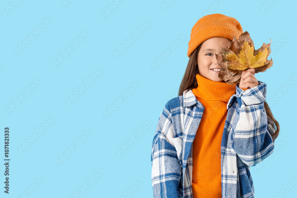 Cute girl in autumn clothes with leaves on blue background Cute girl in autumn clothes with leaves on blue background