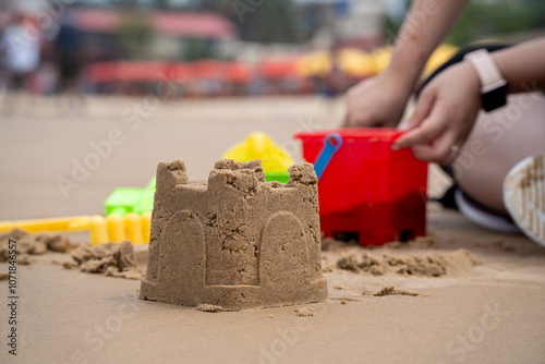 Low side shot showing beautiful sand castle with a woman playing with colorful plastic kit in background showing popular activity at Calangute beach Goa