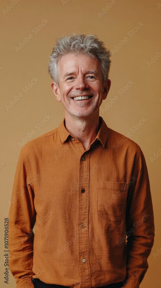 Cheerful mature British man with a vibrant smile standing against a beige background . Vertical portrait Cheerful mature British man with a vibrant smile standing against a beige background . Vertical portrait