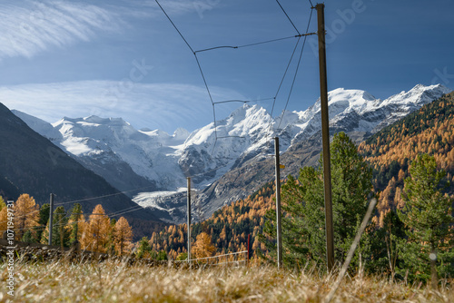 Swiss railway in the Alps of Graubünden in autumn with yellow-colored trees.