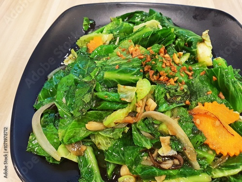 Top view of asian style stir fried vegetables served on a black plate.  photo