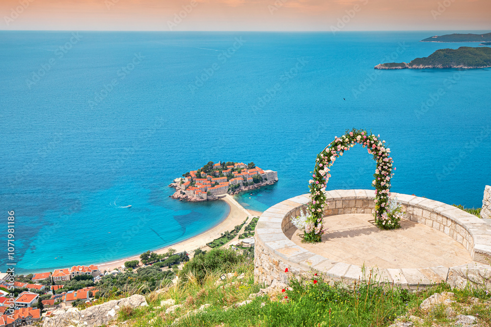 A romantic wedding ceremony at Montenegro Sveti Stefan viewpoint, with an arch adorned in flowers overlooking the Adriatic Sea.