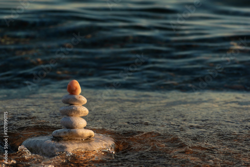 Balance, stability concept. Stones pebbles Zen pyramid of balance standing on stable base is flowing by sea waves Meditation and relaxation practice on beach