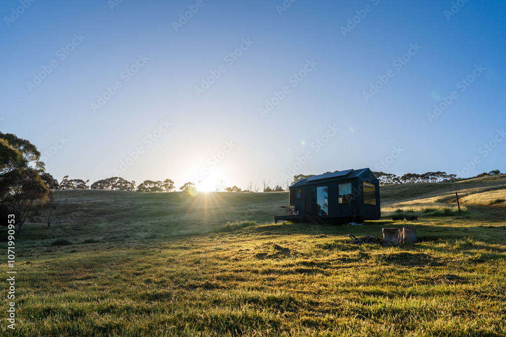 Fototapeta premium Tiny Cabin in early sunrise with sun flare