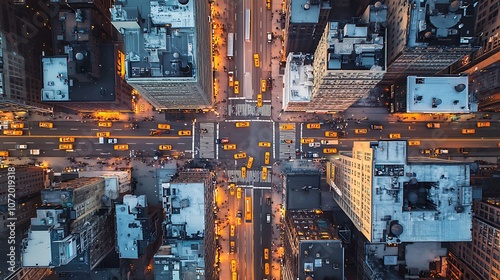 Aerial view of a busy city intersection at dusk, with tall buildings and streetlights.