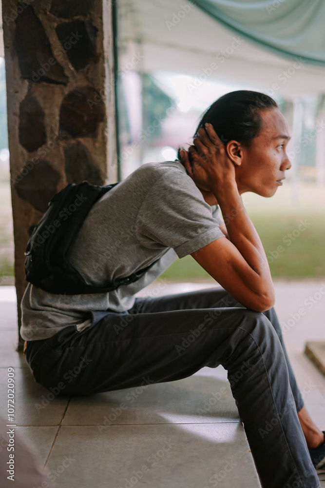 A young man sitting with his head in his hands, expressing stress or deep thought