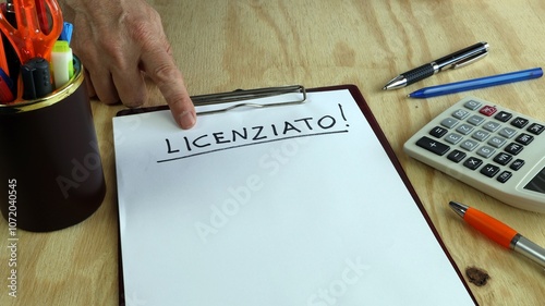 LICENZIATO written in Italian on clipboard and copy space Desk background with stationery calculator and pen and pencils photo