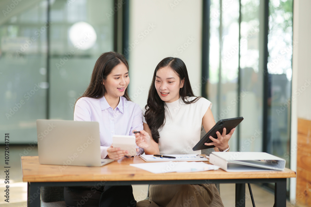 Asian business woman working and talking about graph documents Asian business woman working and talking about graph documents