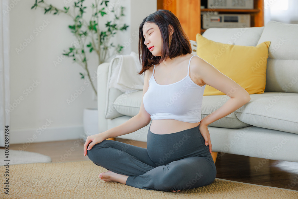 Young Asian happy pregnant woman is sitting and relaxing on bed and touching her back pain. Family plan, pregnancy, motherhood, people and expectation concept Young Asian happy pregnant woman is sitting and relaxing on bed and touching her back pain. Family plan, pregnancy, motherhood, people and expectation concept