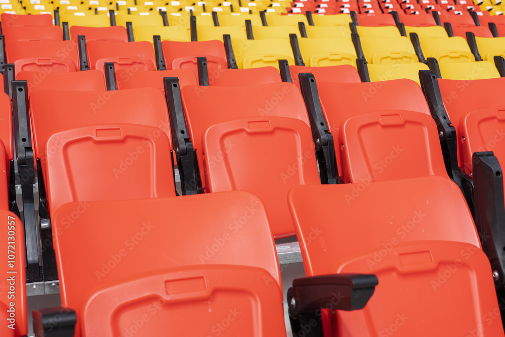 Empty red and yellow seats in the stadium stands Empty red and yellow seats in the stadium stands