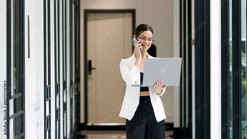 Confident businesswoman working on laptop and talking on phone in office. The concept of business negotiations, consultation and effective work in a modern business environment. Confident businesswoman working on laptop and talking on phone in office. The concept of business negotiations, consultation and effective work in a modern business environment.