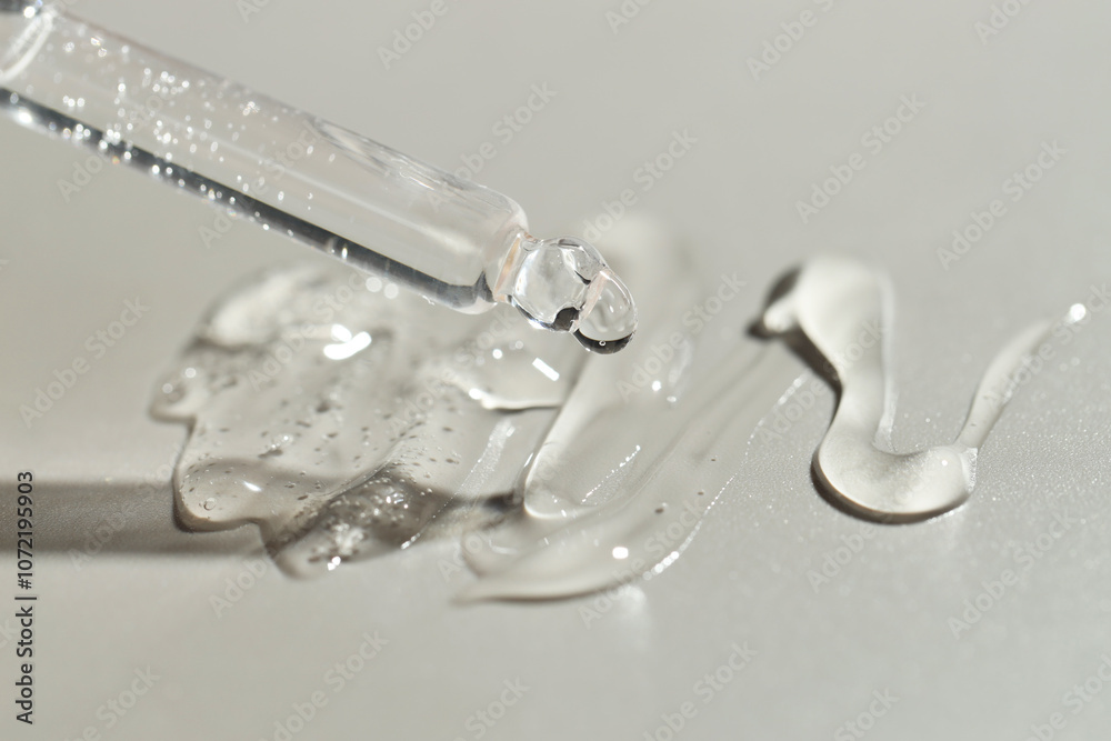 Dripping cosmetic serum from pipette on grey background, closeup Dripping cosmetic serum from pipette on grey background, closeup