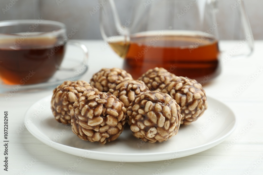 Tasty chocolate puffed rice balls and tea on white wooden table, closeup Tasty chocolate puffed rice balls and tea on white wooden table, closeup