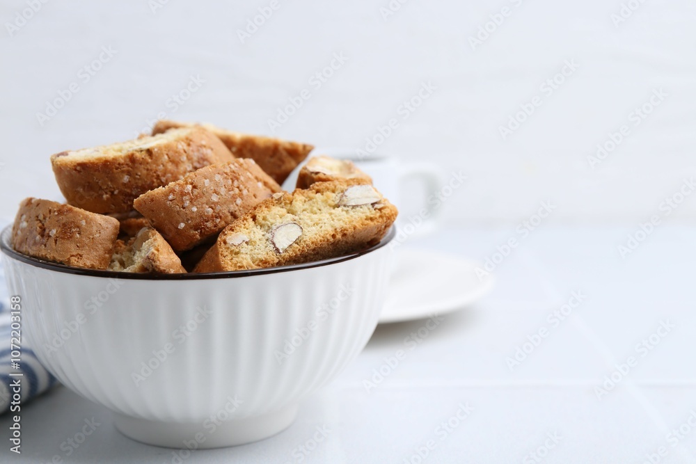Traditional Italian almond biscuits (Cantucci) in bowl on white table, closeup. Space for text Traditional Italian almond biscuits (Cantucci) in bowl on white table, closeup. Space for text