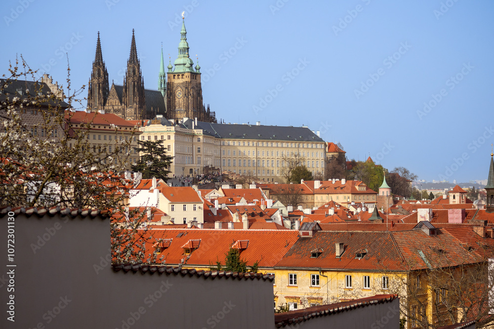 Obraz premium view of the old town church and buildings with red tiled roofs against a blue sky background
