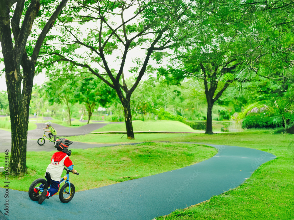 4 years old boy in safety helmeriding balance bike at summer park green trees enjoy happy childhood. .Kids on bicycle in sunny park. Sport for kids. 4 years old boy in safety helmeriding balance bike at summer park green trees enjoy happy childhood. .Kids on bicycle in sunny park. Sport for kids.