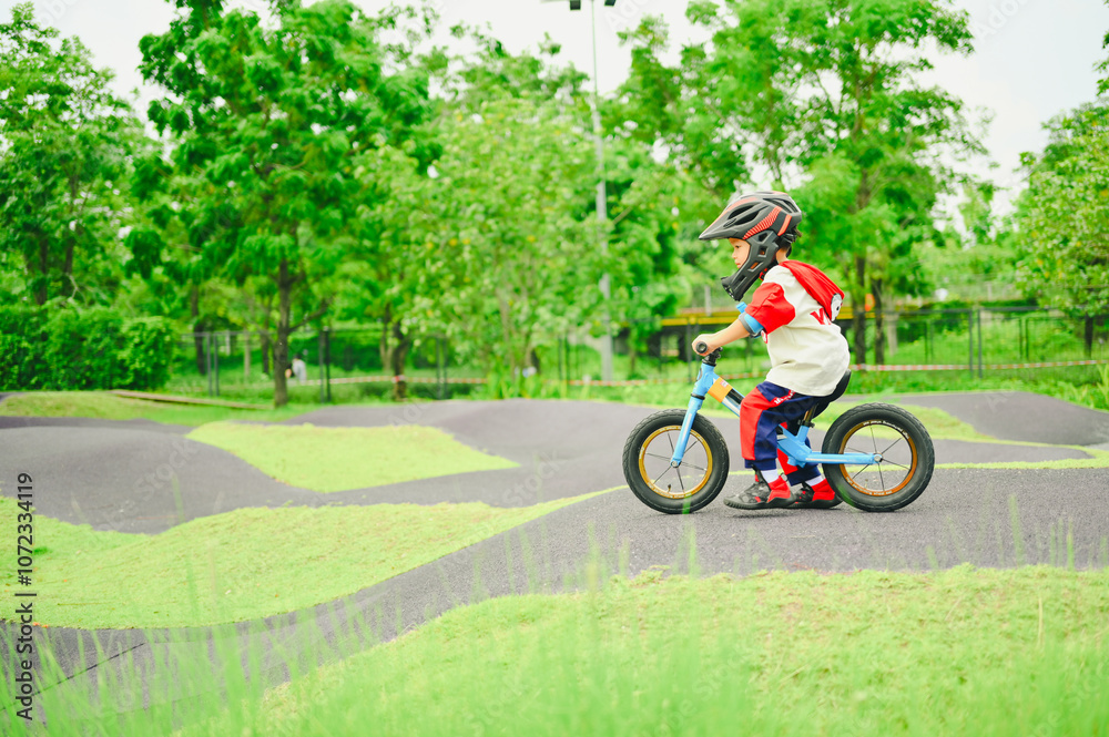 4 years old boy in safety helmeriding balance bike at summer park green trees enjoy happy childhood. .Kids on bicycle in sunny park. Sport for kids.