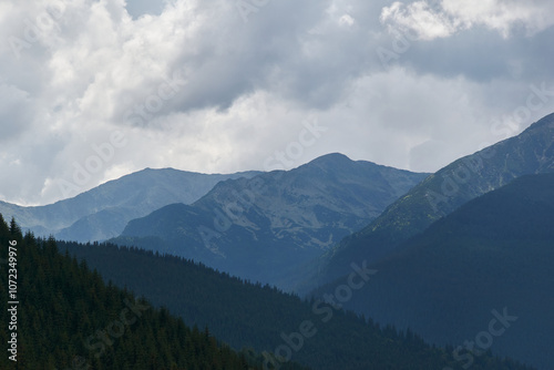 The Parang Mountains with green fir forests and a cloudy sky foretelling a storm in Romania