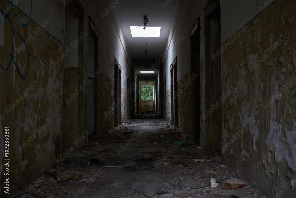 A hallway in an abandoned building with crumbling walls and rubble and a window through which light comes in A hallway in an abandoned building with crumbling walls and rubble and a window through which light comes in