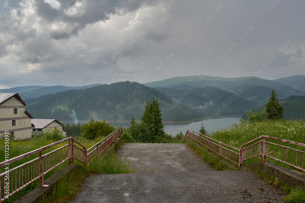 Fototapeta premium Lake Vidra seen from Vidra resort, Valcea with pine forests after rain and fog in Romania
