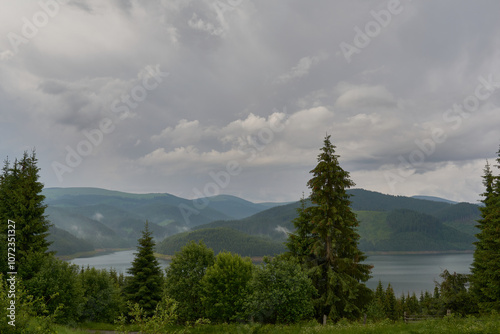 Lake Vidra seen from Vidra resort, Valcea with pine forests after rain and fog in Romania photo