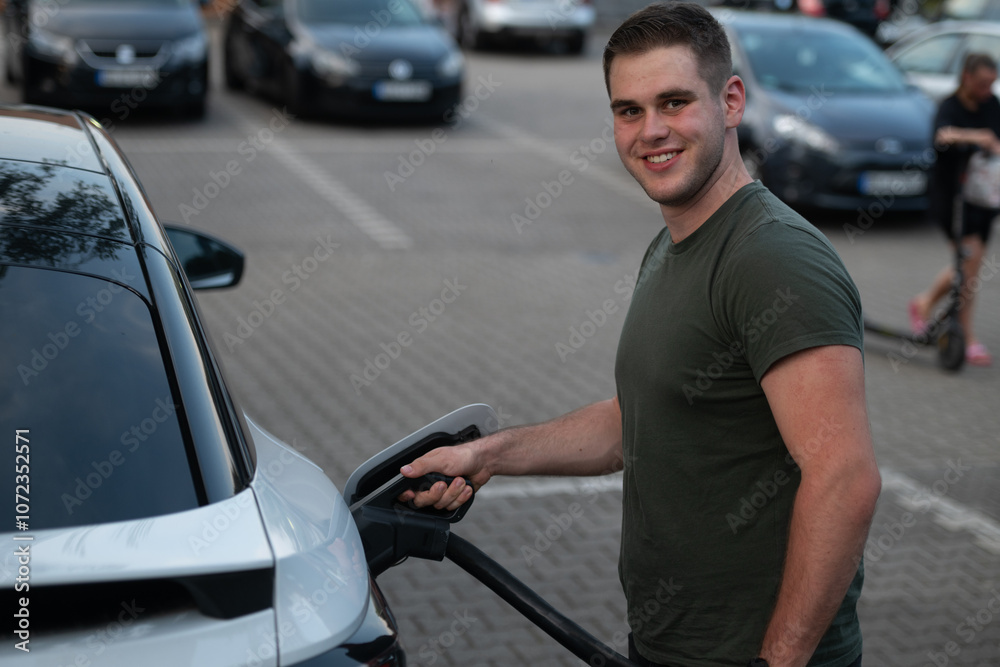 Smiling Man Charging Electric Car in Parking Area Smiling Man Charging Electric Car in Parking Area
