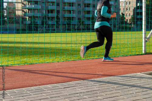 woman running on track near sports field
