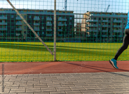 runner on urban sports track with green field
