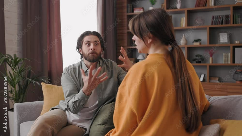 Couple quarrelling sitting on couch at home. Focus on screaming boyfriend. Man and woman are arguing. Misunderstanding, betrayal. Breaking up or divorce, family conflicts, difficult relationships. Couple quarrelling sitting on couch at home. Focus on screaming boyfriend. Man and woman are arguing. Misunderstanding, betrayal. Breaking up or divorce, family conflicts, difficult relationships.