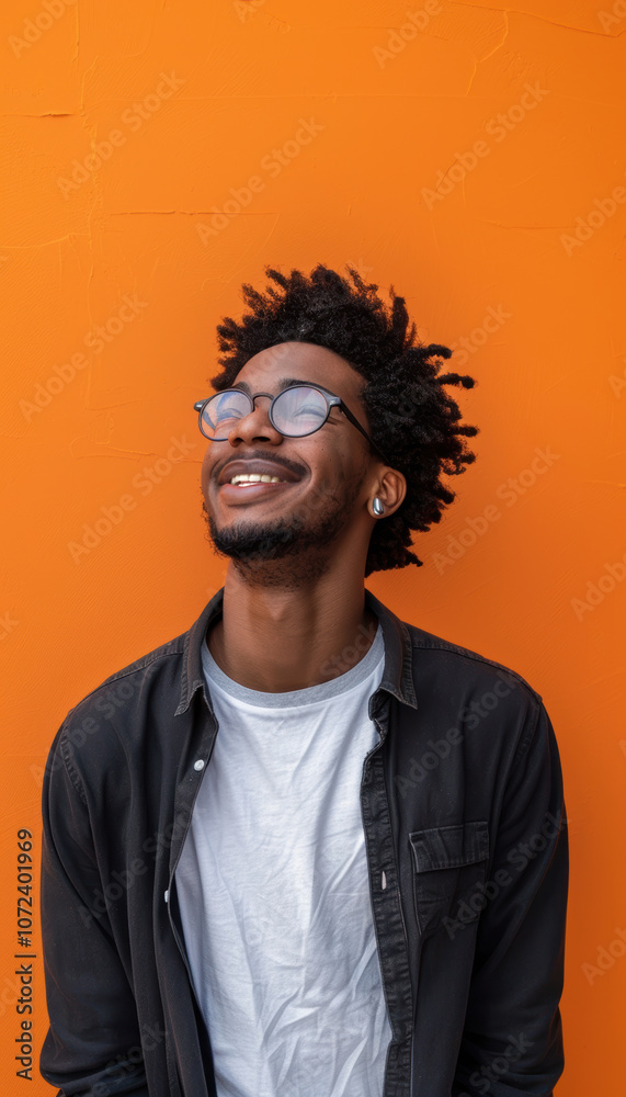 Playful Young Man with Mischievous Grin Against Vibrant Orange Background for Creative Design Playful Young Man with Mischievous Grin Against Vibrant Orange Background for Creative Design