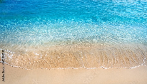 transparent blue water wave on sand beach with sunlight reflections from above abstract blank beach background banner with copy space for summer holidays travel and vacation